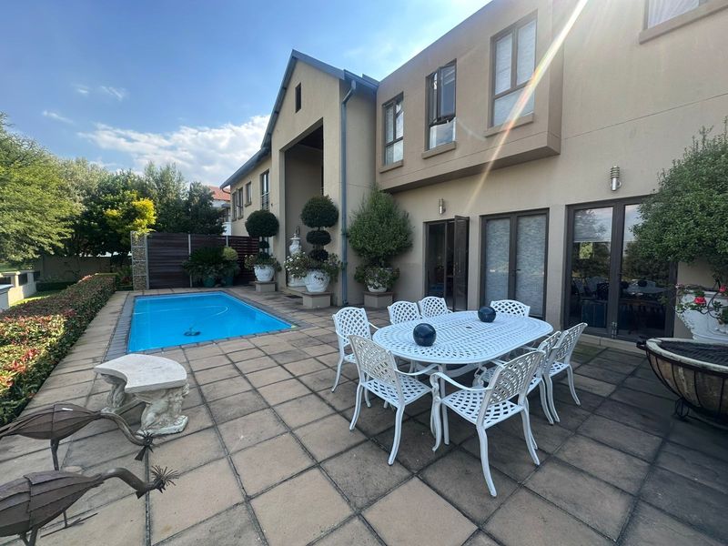 Rear exterior view featuring a paved patio area, swimming pool, and direct access to the home through multiple sliding glass doors.