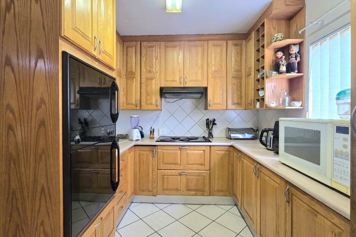 A functional U-shaped kitchen featuring traditional oak cabinetry, built-in oven, electric hob, and tiled finishes, offering a classic layout with ample storage space.