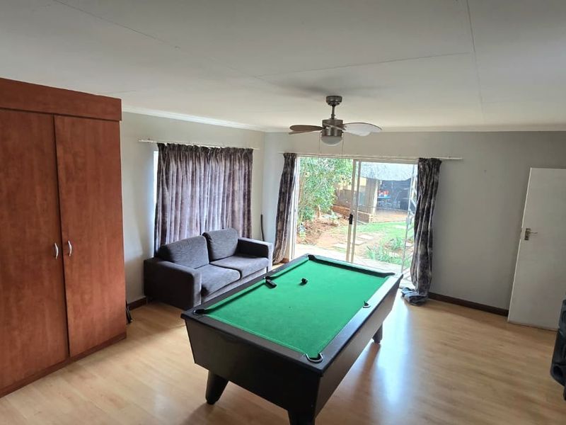A living area featuring laminate flooring, a ceiling fan, and a sliding glass door providing access to the rear garden.