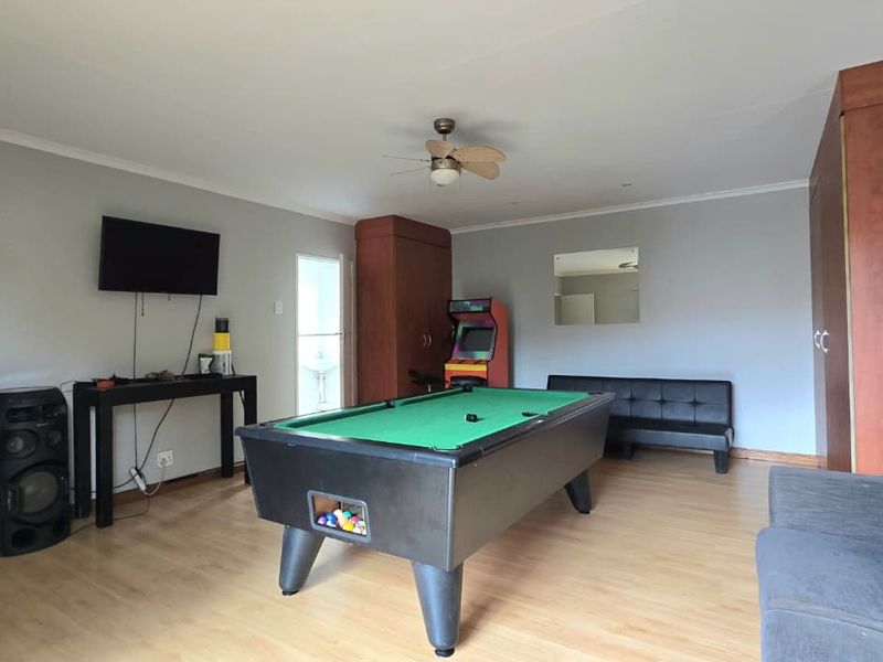 Spacious living area featuring laminate flooring, a ceiling fan, and built-in storage cabinetry, currently utilized as a recreational space.