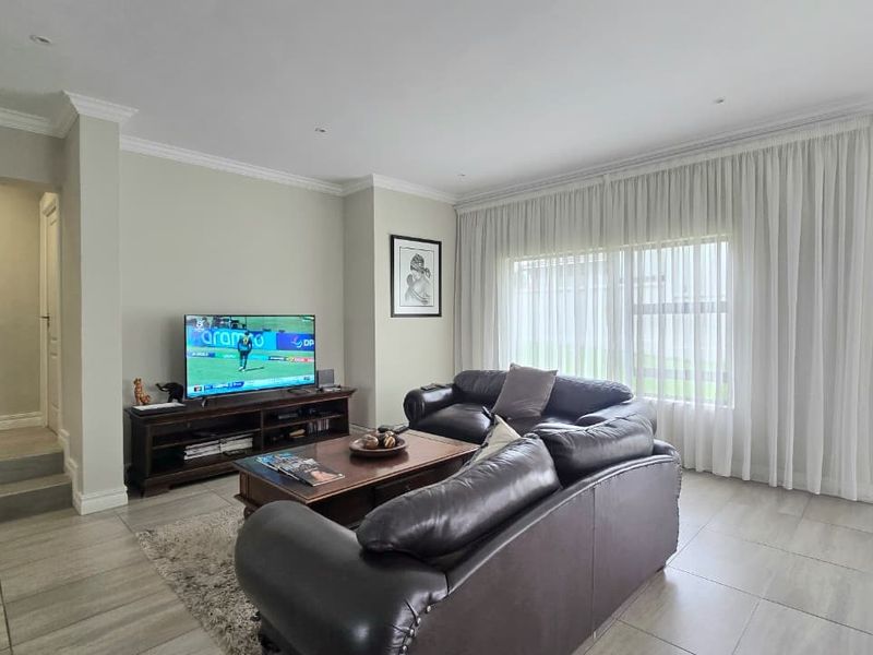 A well-maintained living room featuring neutral wall tones, tiled flooring, and large sliding glass doors that provide access to the outdoor area.