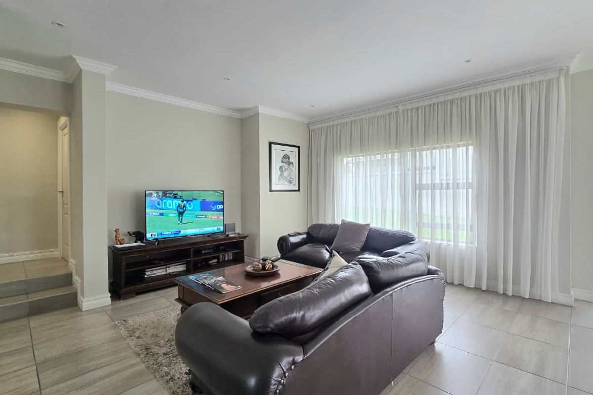 A well-maintained living room featuring neutral wall tones, tiled flooring, and large sliding glass doors that provide access to the outdoor area.
