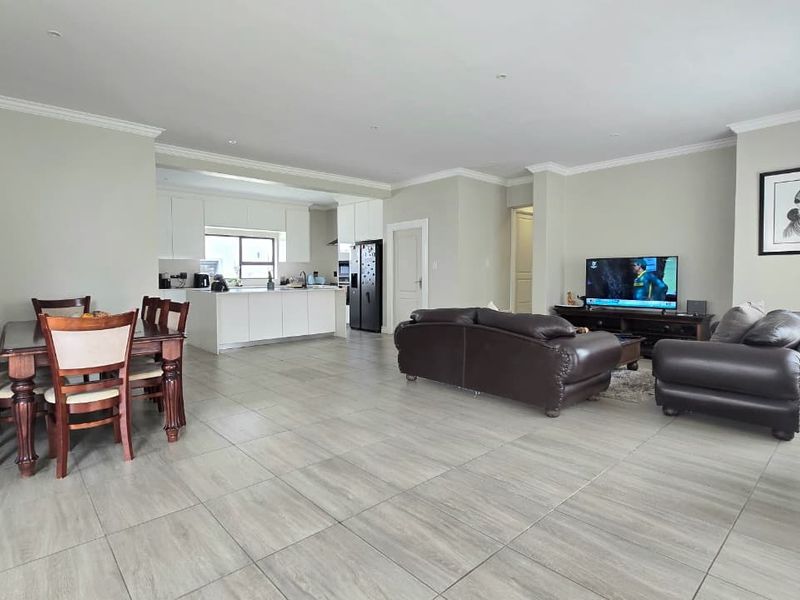 Spacious open-plan living area featuring large format floor tiles, recessed lighting, and a modern kitchen with a central island.