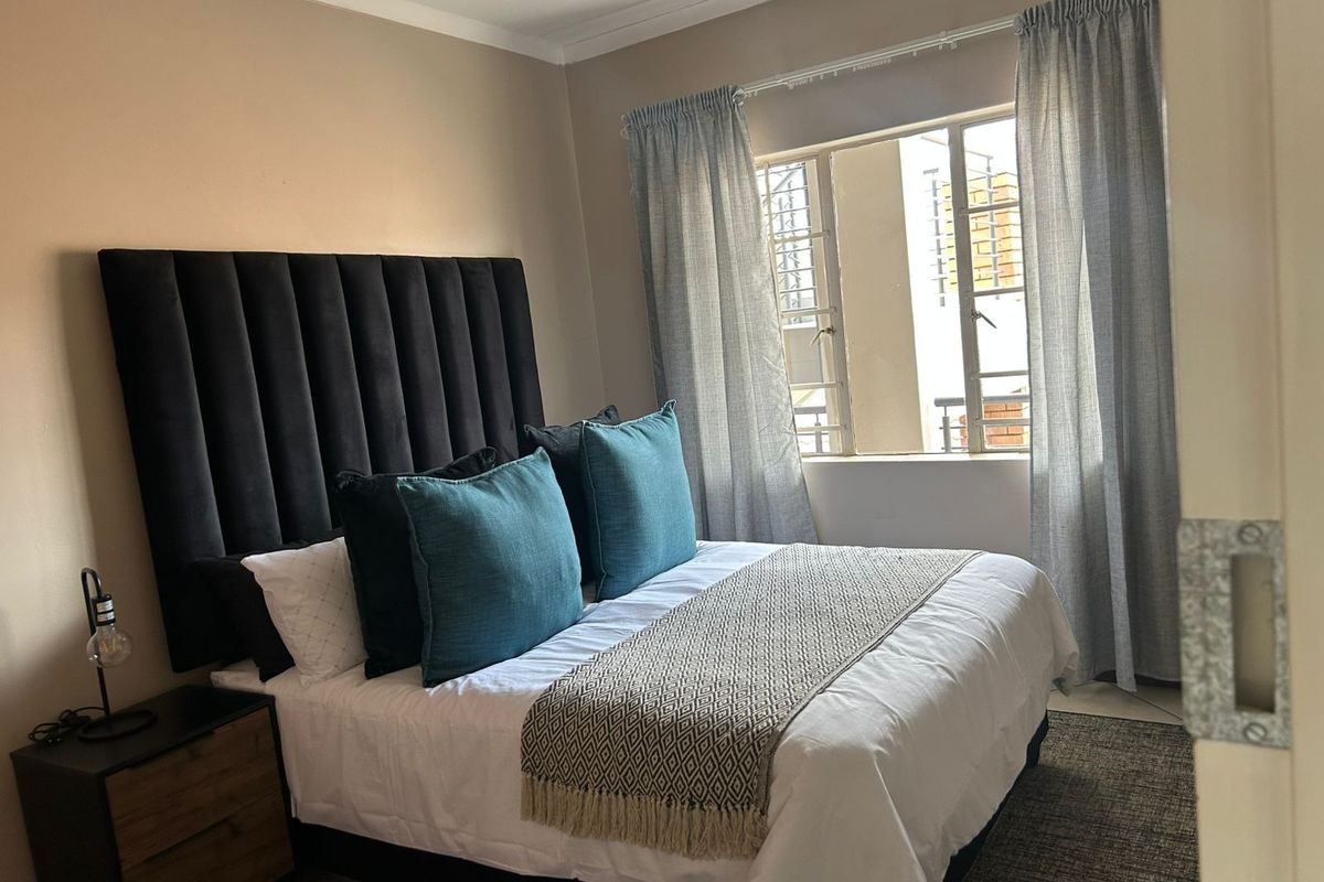 A well-maintained bedroom featuring neutral wall tones, coving, and a window fitted with security bars for added peace of mind.