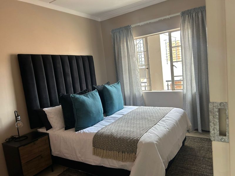 A well-maintained bedroom featuring neutral wall tones, coving, and a window fitted with security bars for added peace of mind.