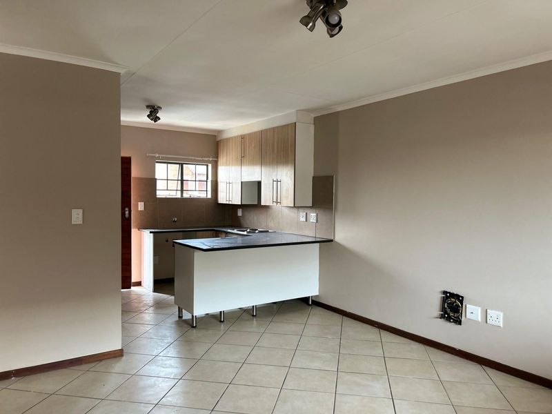 Open-plan kitchen and living area featuring tiled flooring, built-in cabinetry with laminate countertops, and integrated hob with extractor fan.