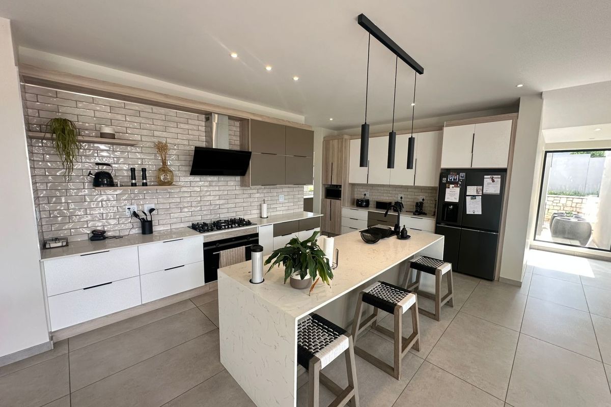 Modern kitchen featuring a central island with quartz countertops, built-in appliances, subway tile backsplash, and contemporary cabinetry with integrated lighting.