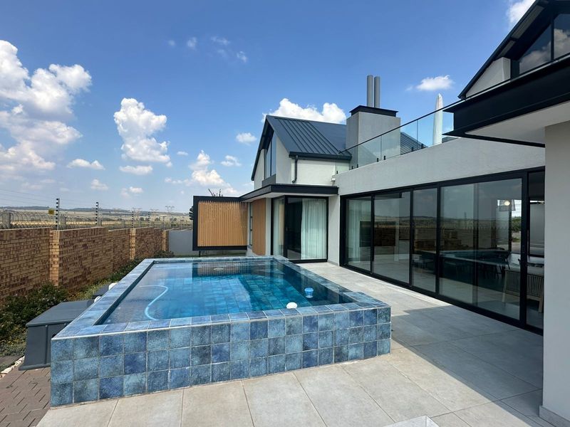Modern outdoor living area featuring a raised tiled swimming pool, expansive glass sliding doors, and a sleek patio, perfect for entertaining.