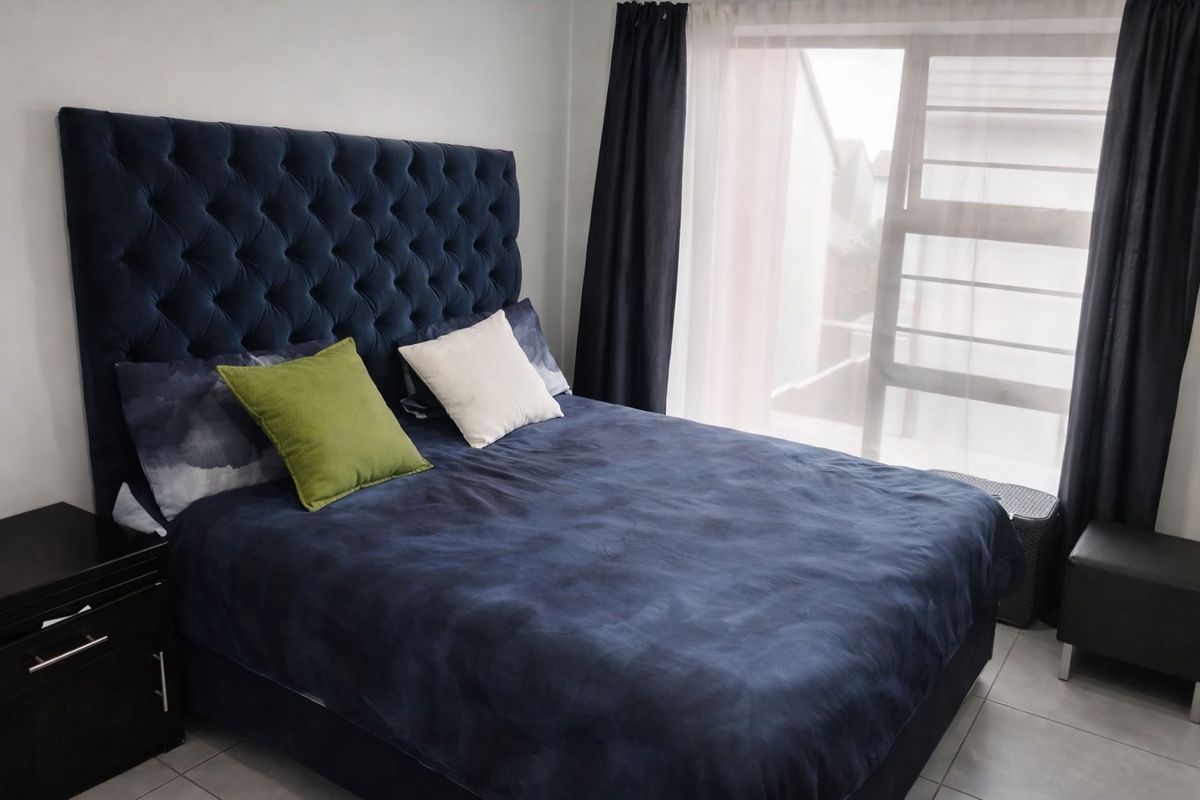 A well-lit bedroom featuring neutral tiled flooring and a large window with installed curtain tracks.