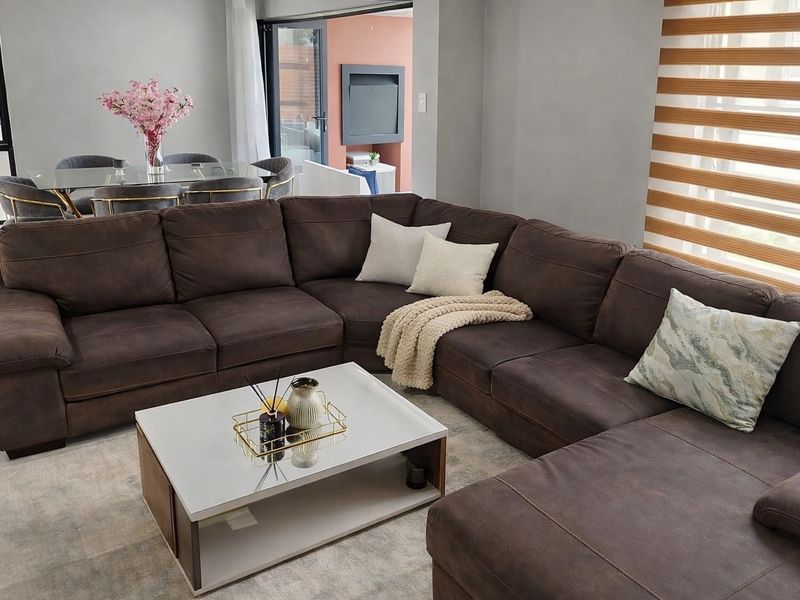 A well-maintained living room featuring tiled flooring, modern zebra blinds, and large sliding glass doors leading to an outdoor patio area.