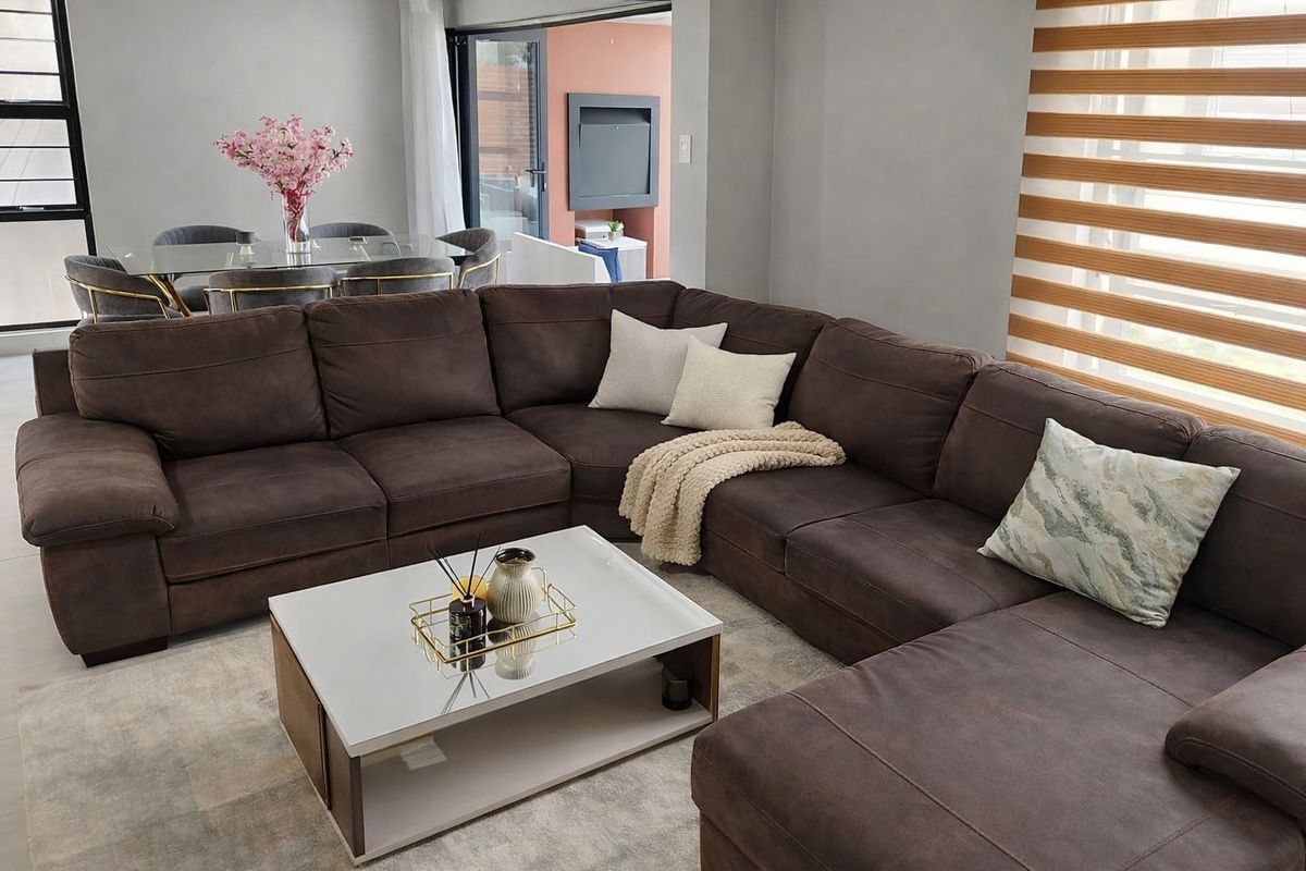 A well-maintained living room featuring tiled flooring, modern zebra blinds, and large sliding glass doors leading to an outdoor patio area.