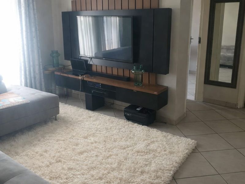 A well-maintained living room featuring a modern built-in media unit and neutral tiled flooring, providing a functional and comfortable living space.