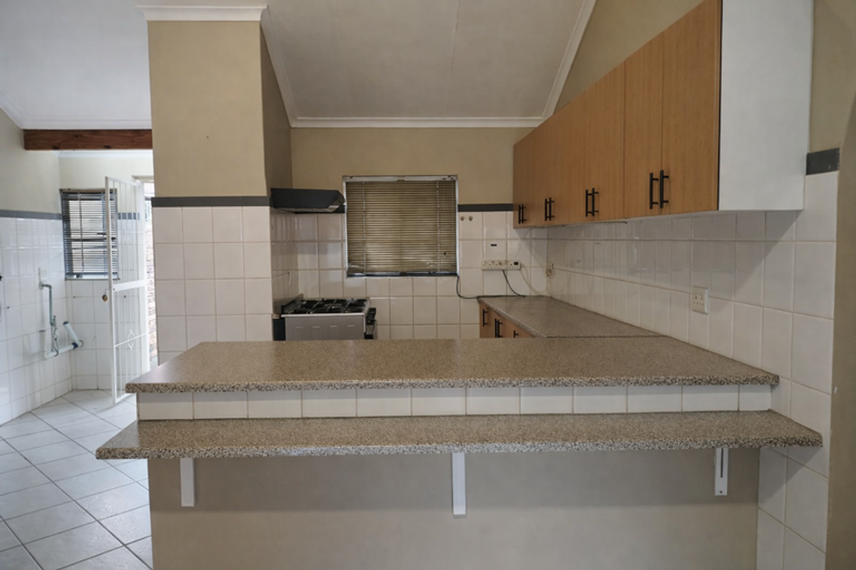 A functional kitchen featuring built-in cabinetry, laminate countertops, a breakfast bar, and tiled finishes, offering a practical layout for daily use.