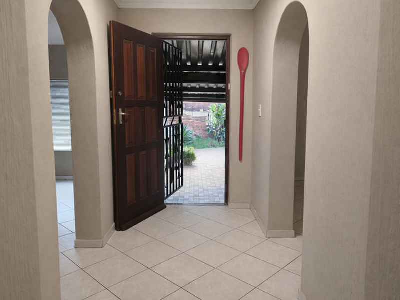 Entrance hall featuring tiled flooring and distinctive arched doorways leading to adjacent living spaces, with direct access to the exterior via a timber door.