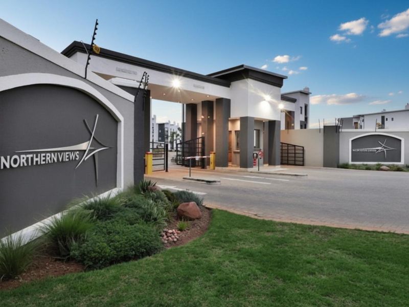 Modern security entrance gatehouse for Northern Views apartment complex, featuring paved access, electric fencing, and well-maintained landscaping.