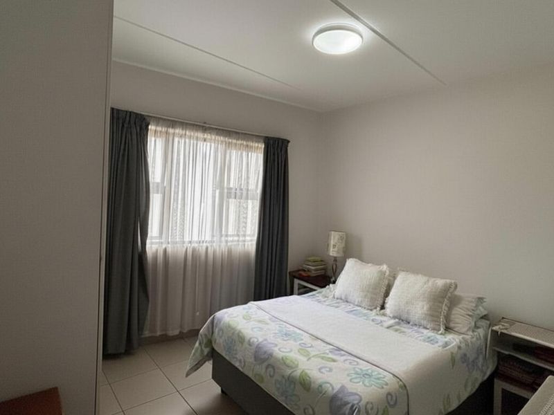 A functional bedroom featuring tiled flooring, a built-in cupboard, and a window with curtain treatments.