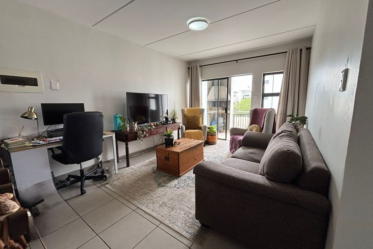 A functional living room featuring tiled flooring and a sliding glass door that provides access to an outdoor balcony area.