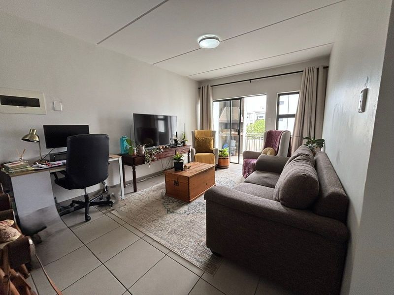 A functional living room featuring tiled flooring and a sliding glass door that provides access to an outdoor balcony area.