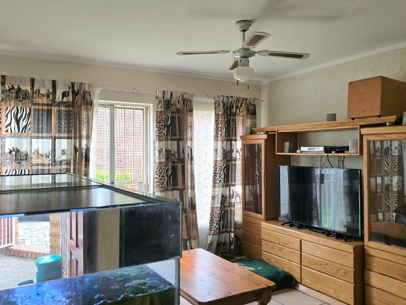 A living room featuring tiled flooring, a ceiling fan, and a sliding glass door providing access to the exterior.
