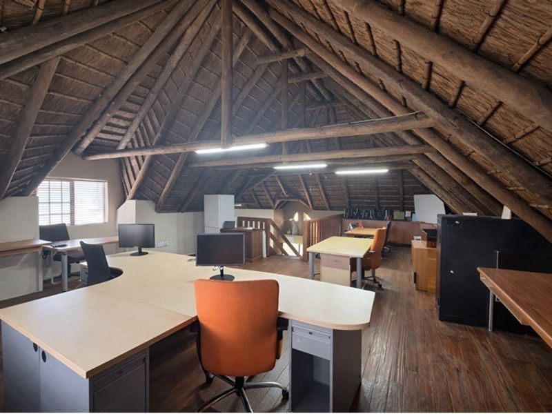Spacious attic-style office featuring exposed timber roof trusses, a traditional thatched ceiling, and warm timber flooring, providing a unique and characterful workspace.