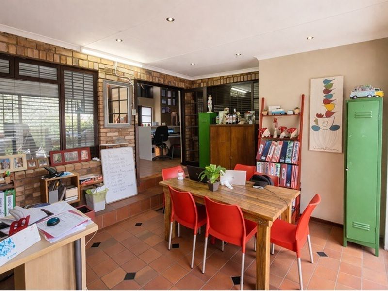 A multi-purpose living area featuring exposed brick walls, terracotta floor tiles, and recessed downlighting, offering a versatile space for dining or home office use.