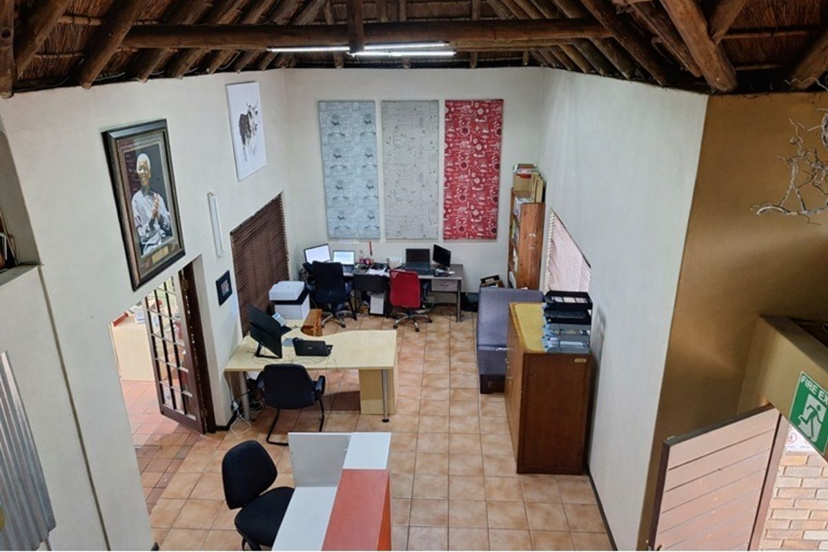 Spacious office area featuring high exposed thatch ceilings, ceramic tile flooring, and natural light, suitable for a professional workspace or home study.