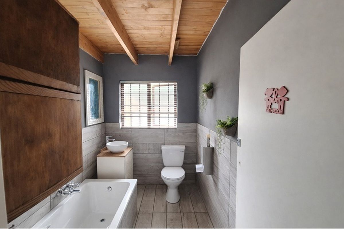 Modern bathroom featuring a vessel sink, built-in bathtub, and exposed timber ceiling beams with neutral wall and floor tiling.