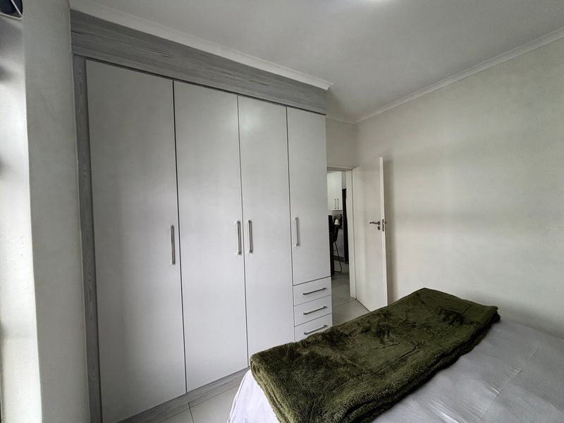 A well-maintained bedroom featuring modern built-in cupboards with clean lines and neutral tiled flooring.