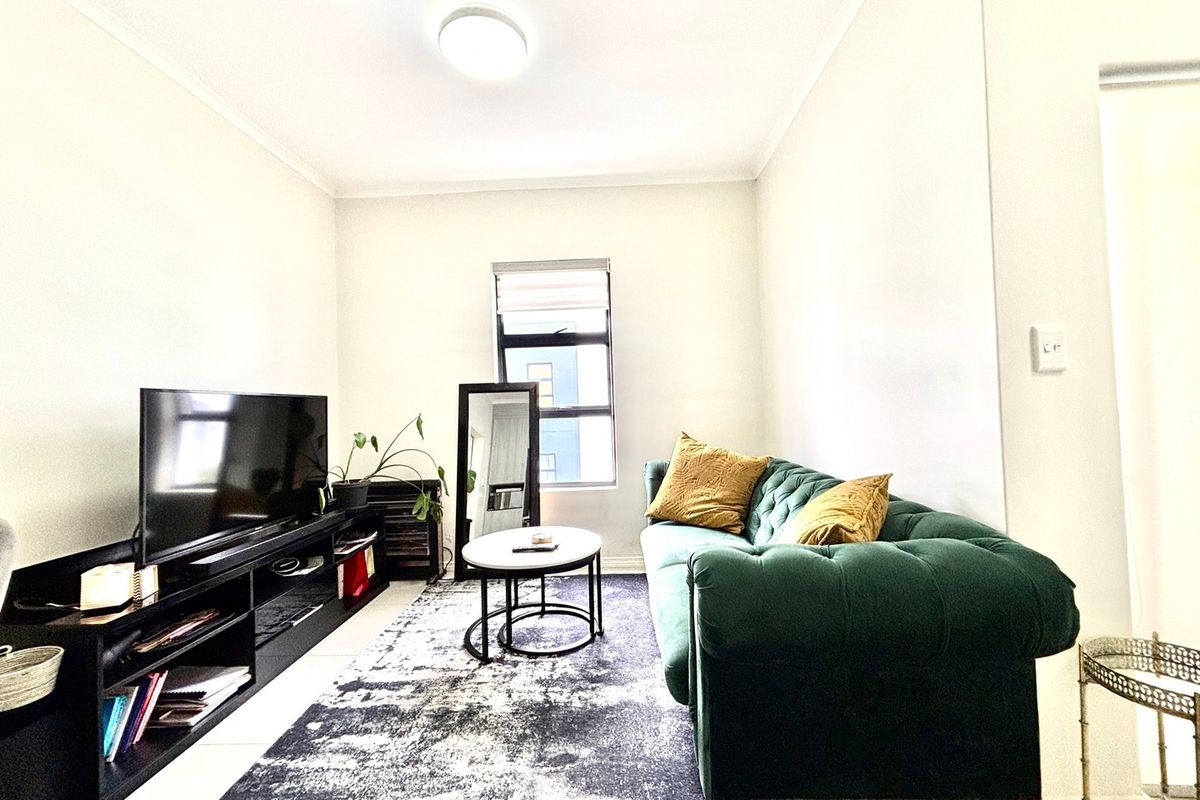 A bright living room featuring tiled flooring, a central flush mount ceiling light, and a window with a fitted roller blind.