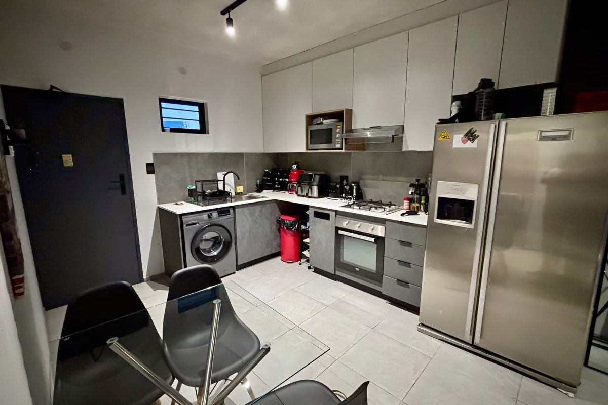 Modern open-plan kitchen featuring sleek cabinetry, integrated appliances, gas hob, and tiled flooring, seamlessly connected to the dining area.