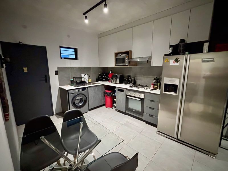Modern open-plan kitchen featuring sleek cabinetry, integrated appliances, gas hob, and tiled flooring, seamlessly connected to the dining area.