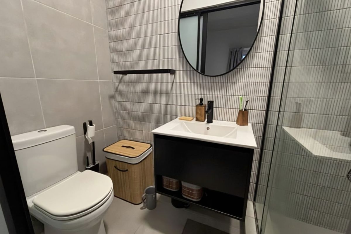 Modern bathroom featuring a sleek vanity cabinet, contemporary wall-mounted mirror, glass shower enclosure, and stylish textured wall tiling.