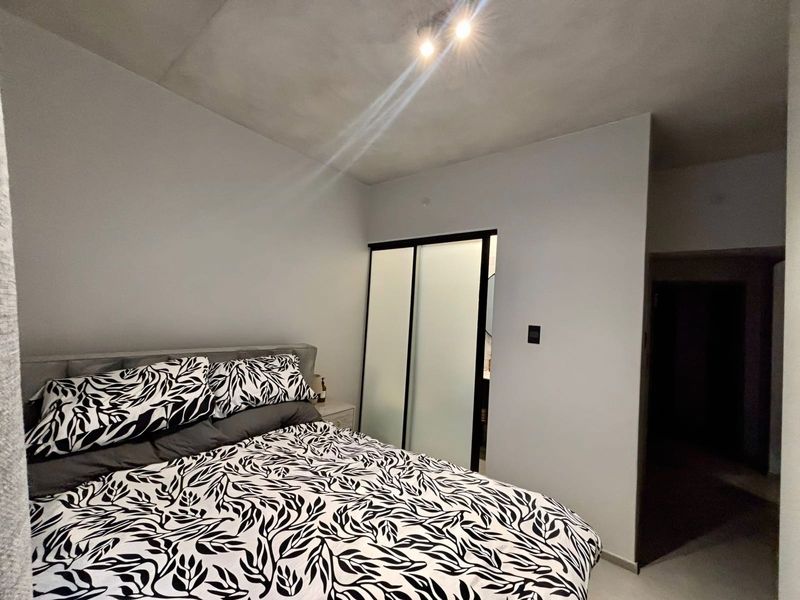 A well-maintained bedroom featuring a modern sliding door wardrobe and recessed ceiling lighting, providing a clean and functional living space.