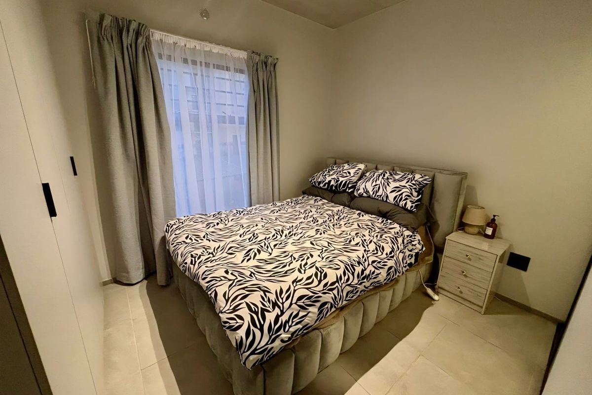 A well-maintained bedroom featuring neutral tiled flooring and a built-in wardrobe, offering a clean and functional living space.