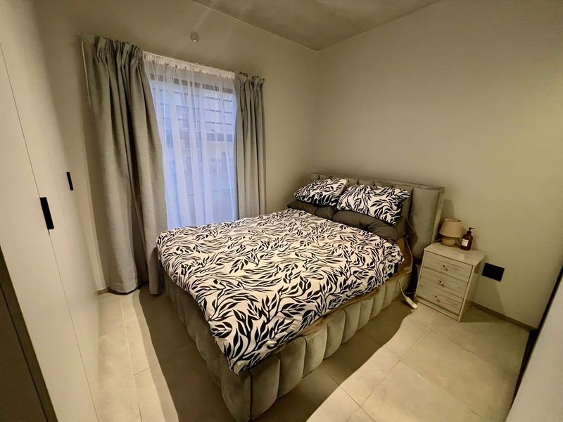 A well-maintained bedroom featuring neutral tiled flooring and a built-in wardrobe, offering a clean and functional living space.
