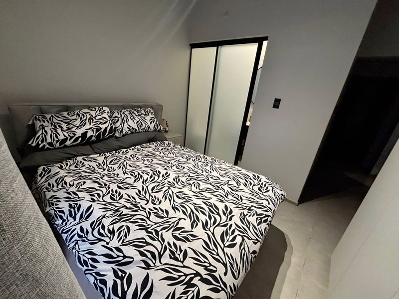 A modern bedroom featuring tiled flooring and a built-in sliding door wardrobe with frosted glass panels.