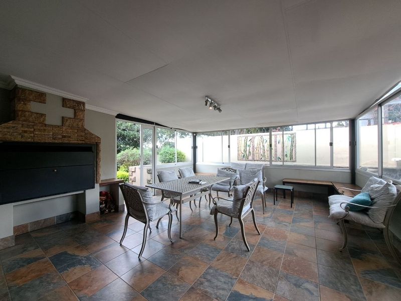 Enclosed patio area featuring a built-in braai, tiled flooring, and large sliding glass doors providing natural light and garden views.