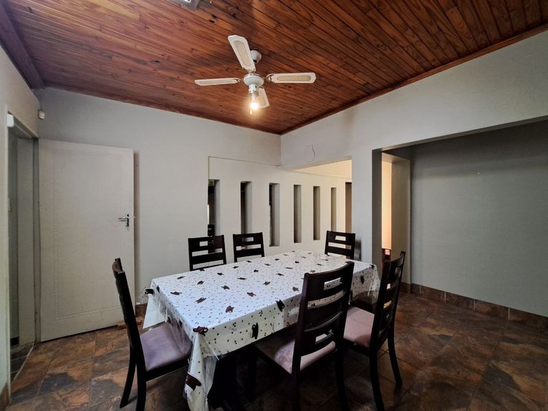 Dining room featuring a warm timber ceiling, ceiling fan, tiled flooring, and unique decorative wall cutouts connecting to adjacent living spaces.