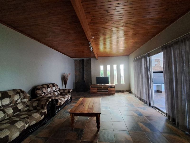 Spacious living room featuring a warm wood-paneled ceiling, tiled floors, a built-in fireplace, and large sliding doors providing access to the outdoor area.