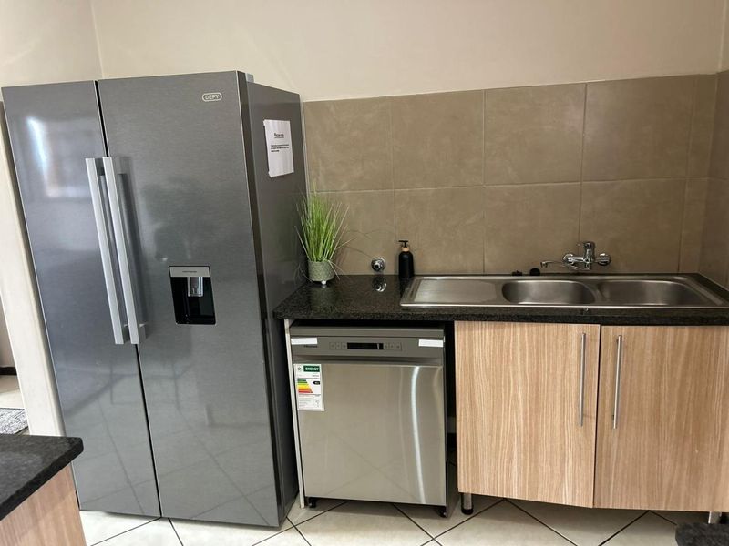 A functional kitchen area featuring granite countertops, a double sink with mixer tap, tiled backsplash, and modern cabinetry.