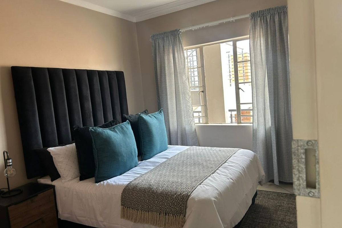 A well-lit bedroom featuring neutral wall tones and a window with curtain rails, providing a comfortable and functional sleeping space.
