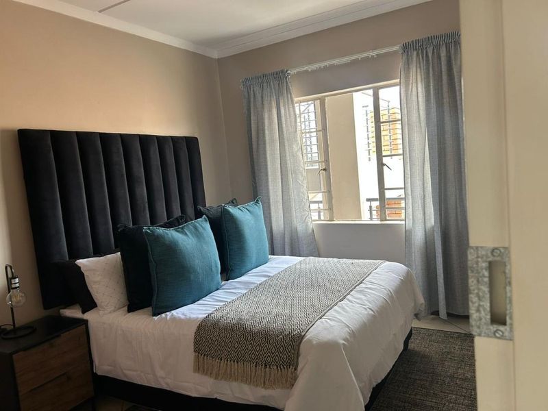 A well-lit bedroom featuring neutral wall tones and a window with curtain rails, providing a comfortable and functional sleeping space.