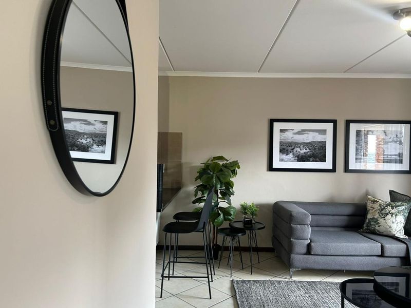 An open-plan living area featuring neutral wall tones, tiled flooring, and a drop ceiling, creating a comfortable and functional space.