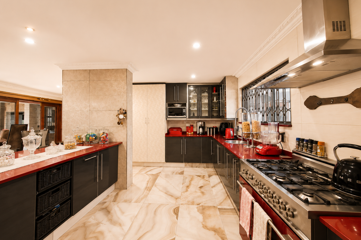 Modern kitchen featuring dark cabinetry, contrasting red countertops, large format marble-look floor tiles, and high-end stainless steel gas cooking appliances.
