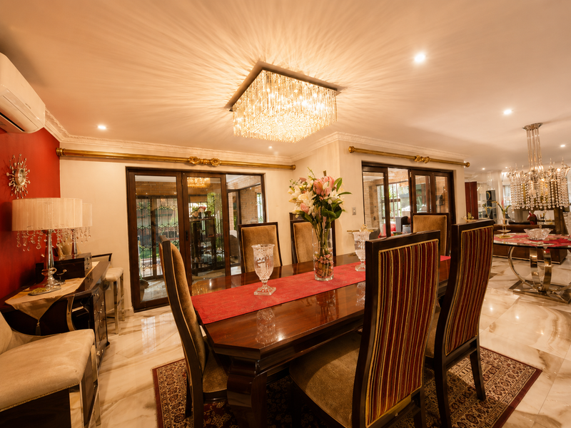 Elegant dining room featuring polished marble flooring, a grand crystal chandelier, and sliding glass doors providing access to the outdoor area.