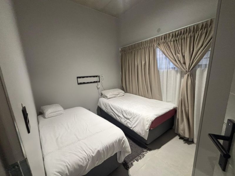 A functional bedroom featuring tiled flooring and neutral wall finishes, suitable for a guest room or children's bedroom.