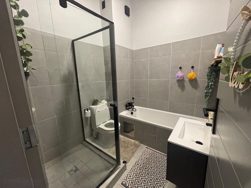 Modern bathroom featuring a glass-enclosed shower, built-in bathtub, and a sleek wall-mounted vanity with grey tiled walls.