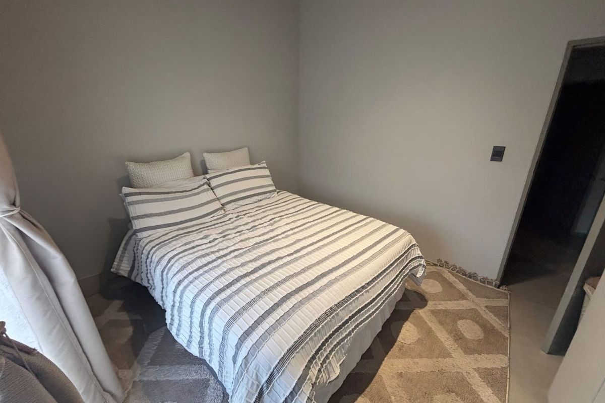A neutral-toned bedroom featuring smooth wall finishes and tiled flooring, providing a clean and simple space.