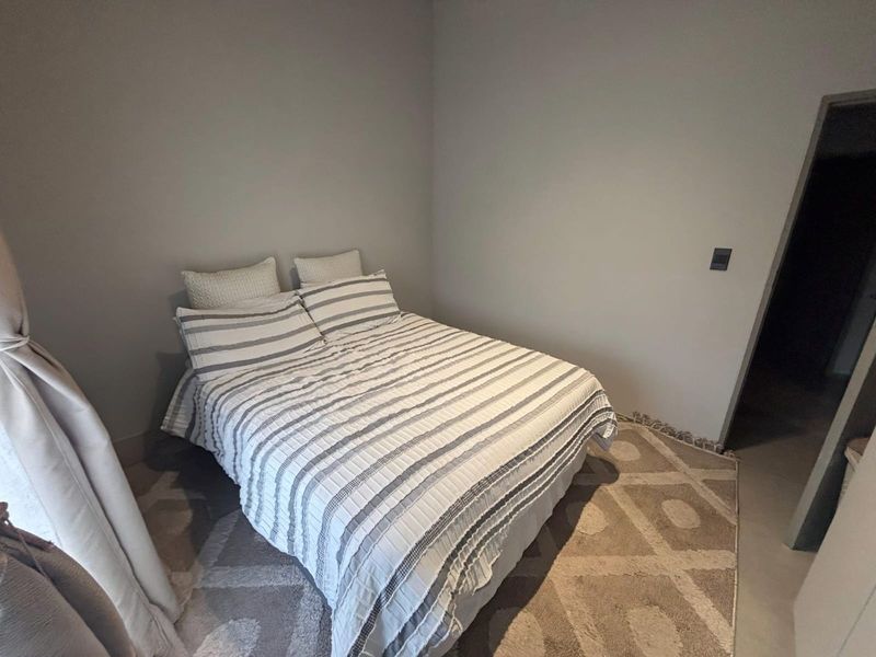 A neutral-toned bedroom featuring smooth wall finishes and tiled flooring, providing a clean and simple space.