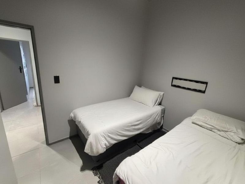 A simple bedroom featuring neutral grey walls and tiled flooring, providing a clean and functional space.